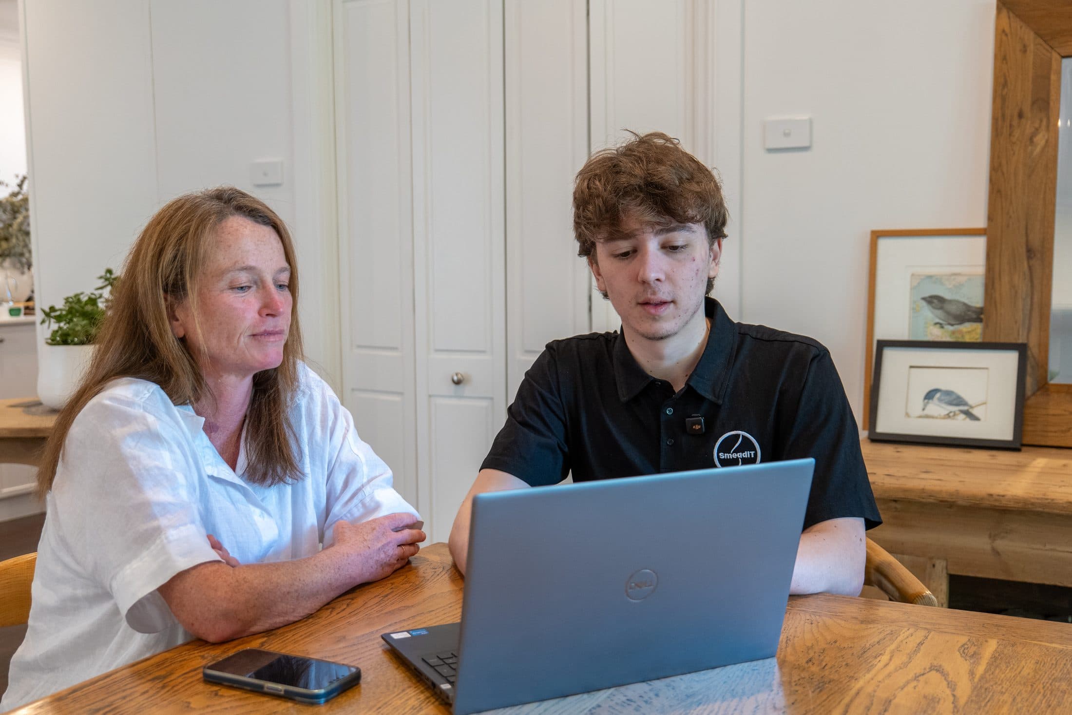 A technician showing a customer something on a laptop at home